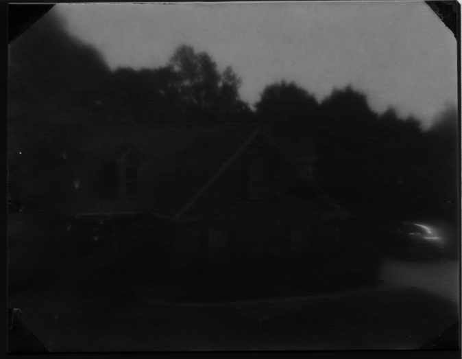 The positive of the image that my camera got. Only the sky is really visible. There trees appear black. There is a very faint image of a house.